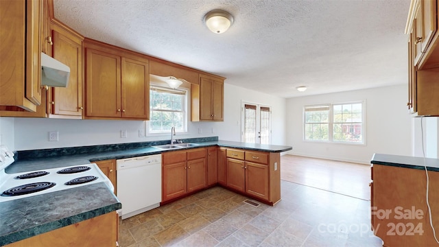 kitchen featuring white appliances, a textured ceiling, sink, and kitchen peninsula