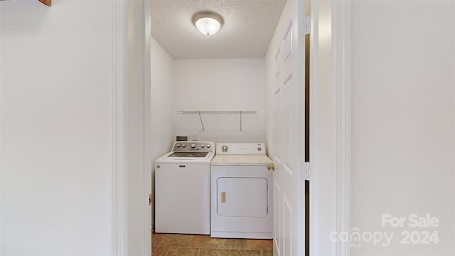 clothes washing area featuring independent washer and dryer, a textured ceiling, and light tile patterned flooring