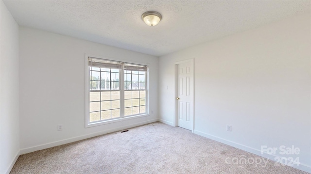 carpeted spare room featuring a textured ceiling