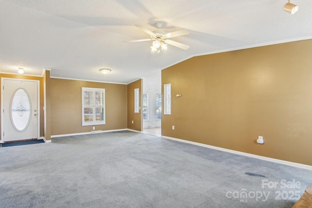 interior space featuring lofted ceiling, carpet floors, ornamental molding, ceiling fan, and a textured ceiling