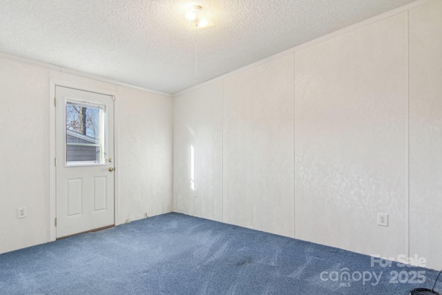 empty room with ornamental molding, a textured ceiling, and carpet flooring