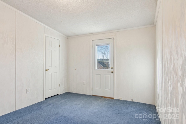 unfurnished room featuring crown molding, carpet, and a textured ceiling