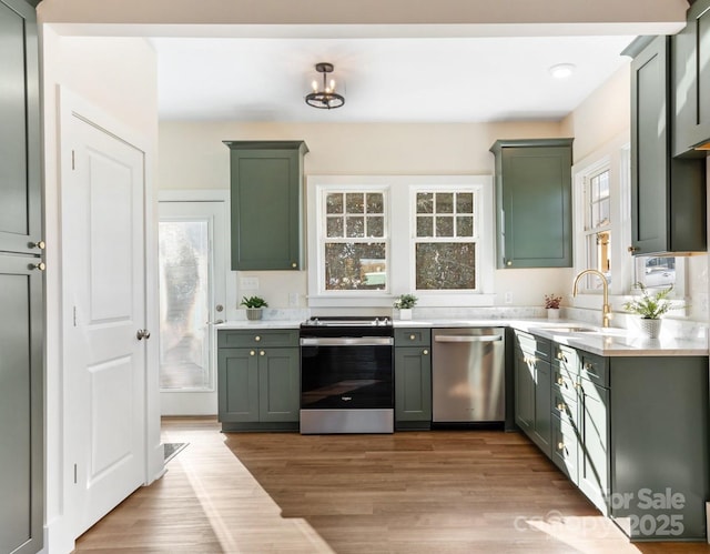 kitchen featuring green cabinetry, stainless steel appliances, light wood-type flooring, and sink