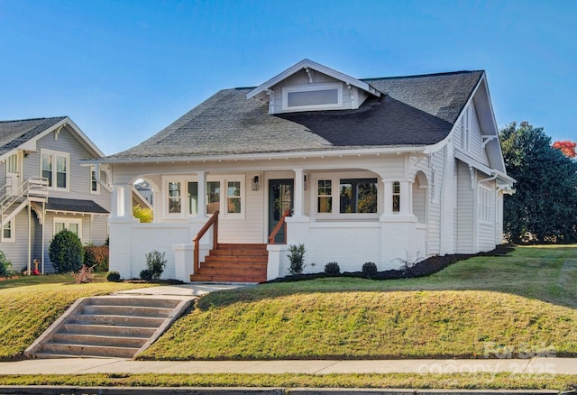 bungalow-style home featuring brick siding, a shingled roof, and a front yard