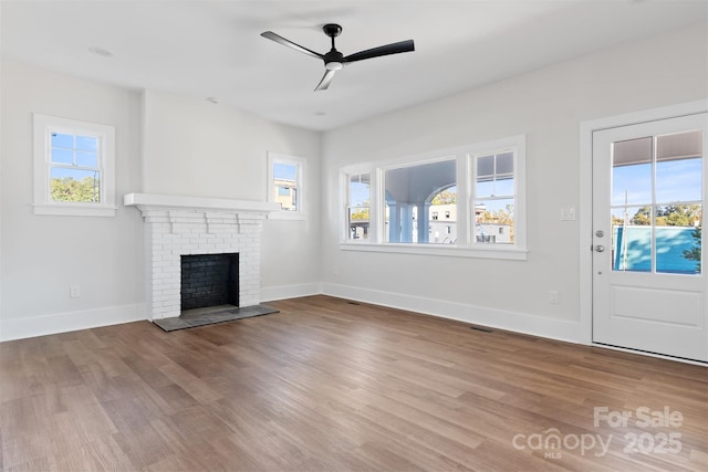 unfurnished living room featuring a brick fireplace, hardwood / wood-style flooring, and ceiling fan