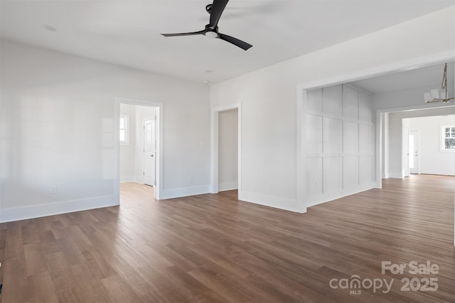 empty room with ceiling fan, baseboards, and wood finished floors