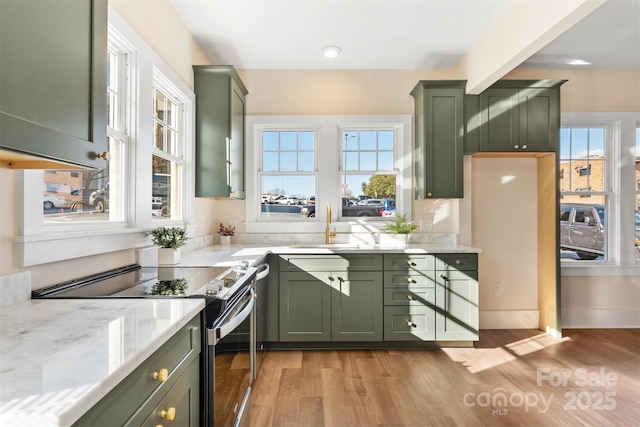 kitchen with light wood-type flooring, a wealth of natural light, green cabinetry, and stainless steel electric stove