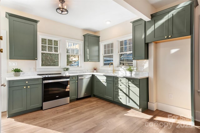 kitchen with stainless steel appliances, light countertops, light wood-style flooring, and green cabinets