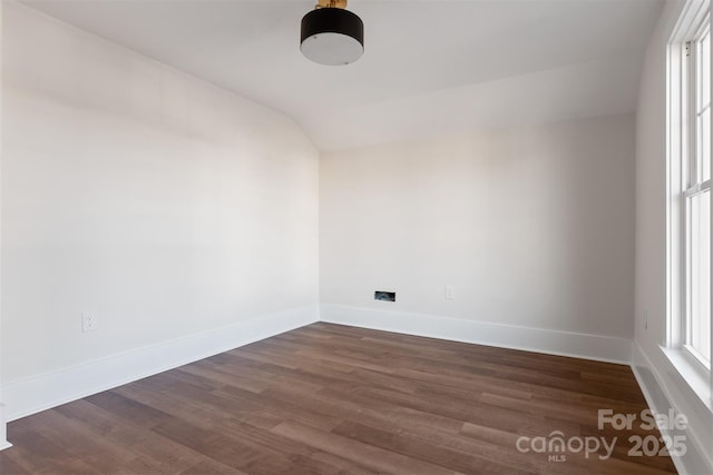 spare room with baseboards, vaulted ceiling, and dark wood-type flooring