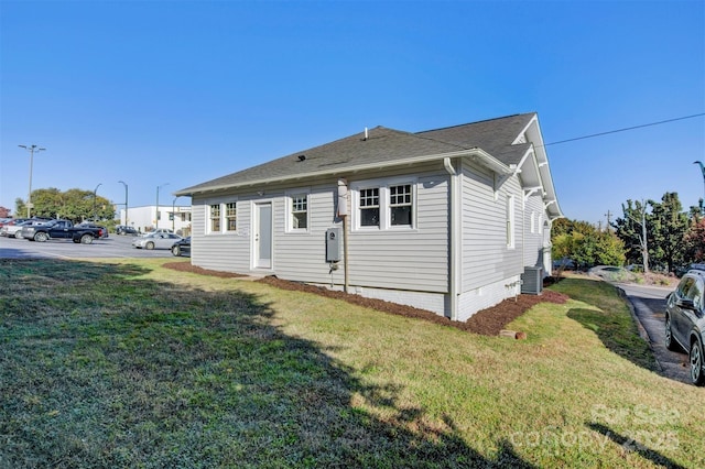 view of side of property with central AC unit and a yard