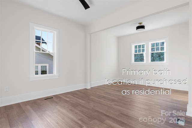 unfurnished room featuring visible vents, baseboards, and wood finished floors