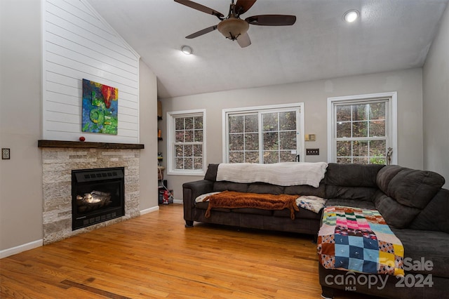 living room featuring a fireplace, light hardwood / wood-style floors, ceiling fan, and vaulted ceiling