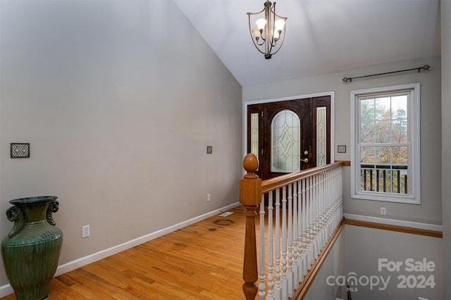 entrance foyer with hardwood / wood-style floors, vaulted ceiling, and a notable chandelier