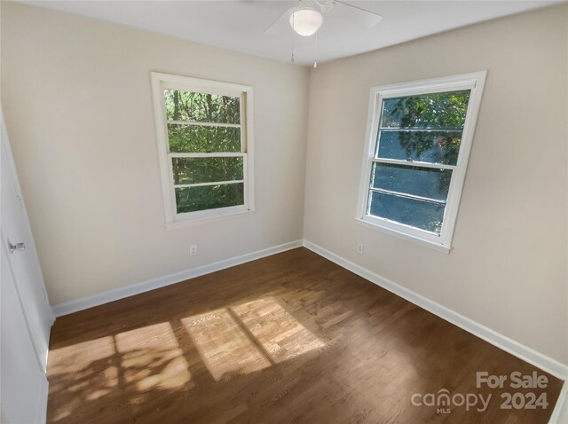 spare room featuring baseboards, plenty of natural light, dark wood finished floors, and ceiling fan