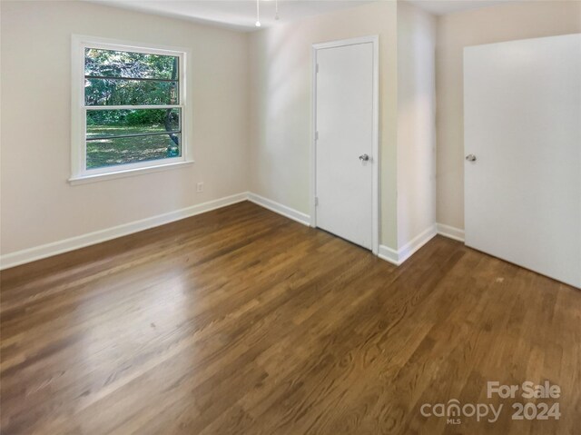 unfurnished bedroom with baseboards and dark wood-style floors