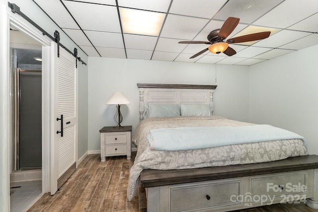 127 Lake View Dr, New London, NC 28127 - bedroom featuring a barn door, wood finished floors, a closet, a ceiling fan, and a paneled ceiling