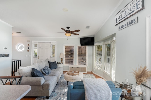 living room featuring vaulted ceiling, hardwood / wood-style flooring, ceiling fan, and crown molding