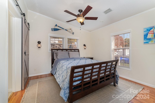 127 Lake View Dr, New London, NC 28127 - bedroom with a barn door, light wood-style flooring, ornamental molding, multiple windows, and baseboards