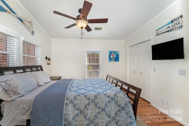 bedroom with hardwood / wood-style flooring, ceiling fan, multiple windows, and a closet