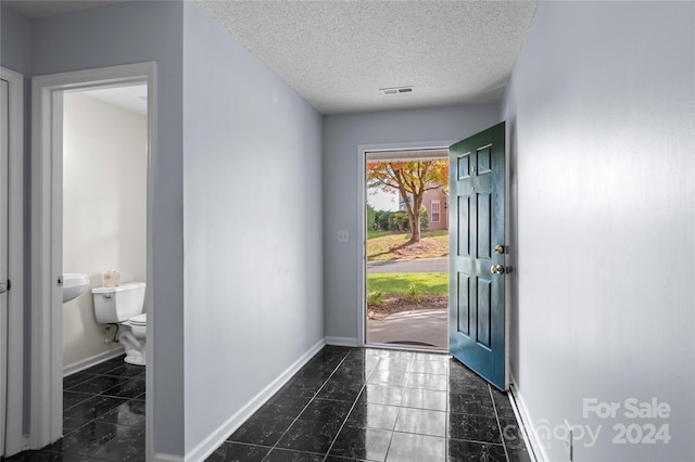 entrance foyer with dark tile patterned floors and a textured ceiling