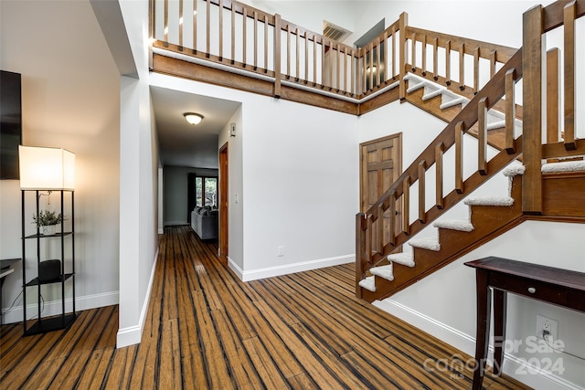 stairs with hardwood / wood-style floors and a high ceiling