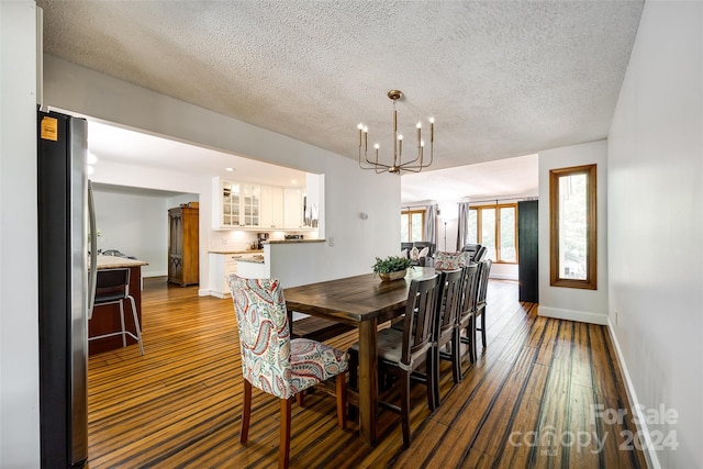 dining space featuring a textured ceiling, an inviting chandelier, and dark wood-type flooring