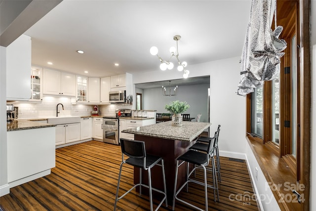 kitchen featuring white cabinets, appliances with stainless steel finishes, decorative light fixtures, and a chandelier