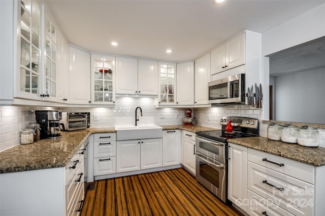 kitchen with white cabinetry, sink, appliances with stainless steel finishes, and dark stone counters