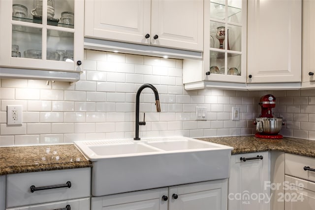 kitchen featuring backsplash, sink, white cabinets, and dark stone counters