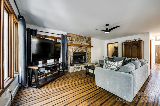 living room featuring hardwood / wood-style flooring, ceiling fan, a stone fireplace, and a wealth of natural light