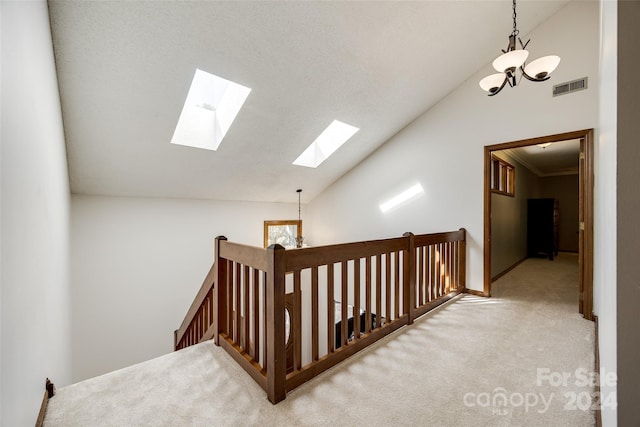 corridor featuring light colored carpet, crown molding, a notable chandelier, and vaulted ceiling with skylight