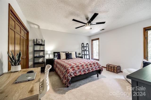 bedroom with ceiling fan, carpet floors, a textured ceiling, and a closet