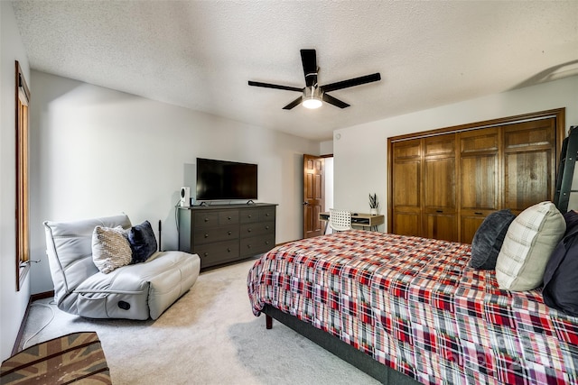 bedroom with ceiling fan, a closet, light carpet, and a textured ceiling