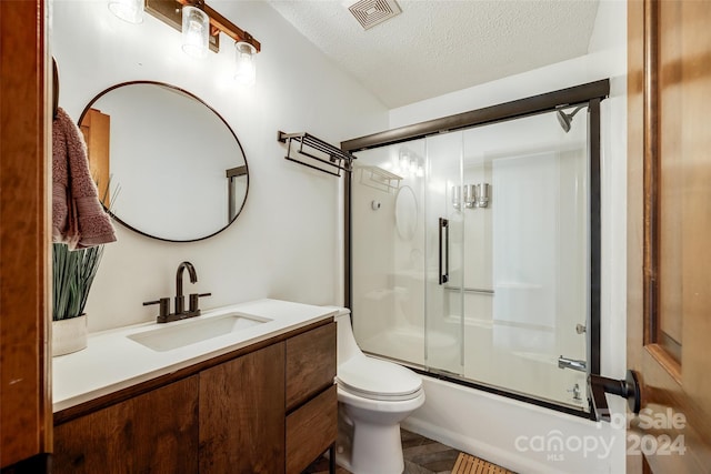 full bathroom featuring shower / bath combination with glass door, vanity, a textured ceiling, and toilet