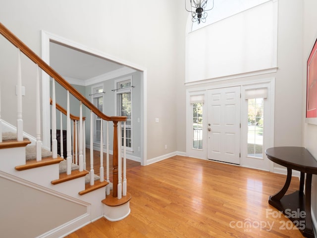 entrance foyer with crown molding, light hardwood / wood-style flooring, and a high ceiling