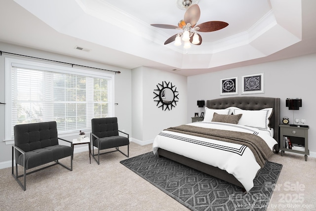 carpeted bedroom with a tray ceiling, ornamental molding, and ceiling fan