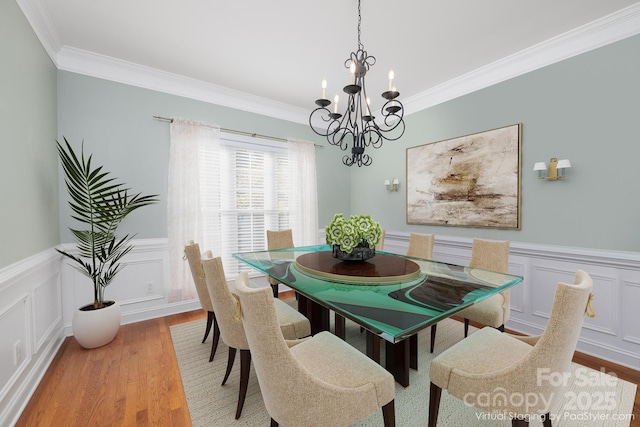 dining space featuring ornamental molding, a chandelier, and light hardwood / wood-style flooring