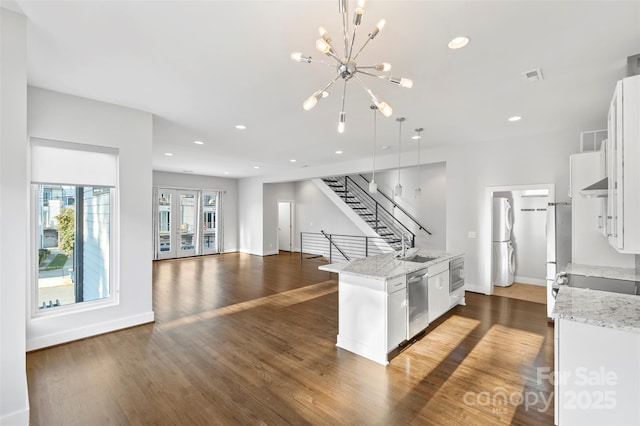 kitchen with stainless steel appliances, a center island with sink, white cabinets, dark hardwood / wood-style floors, and hanging light fixtures