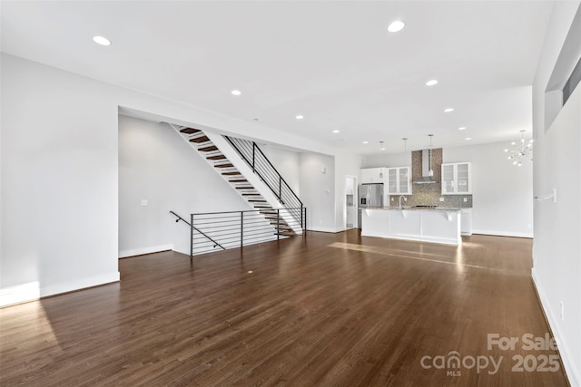 unfurnished living room with a notable chandelier and dark hardwood / wood-style flooring