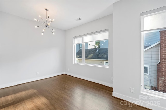 unfurnished room with dark wood-type flooring and a notable chandelier