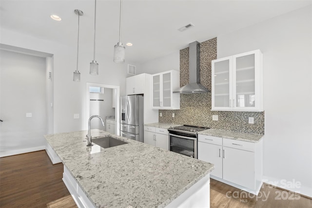 kitchen featuring pendant lighting, white cabinets, sink, wall chimney exhaust hood, and stainless steel appliances