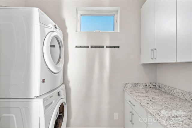 washroom featuring cabinets and stacked washer / dryer