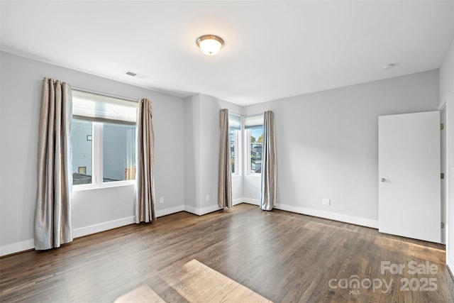 spare room with dark hardwood / wood-style flooring and a healthy amount of sunlight