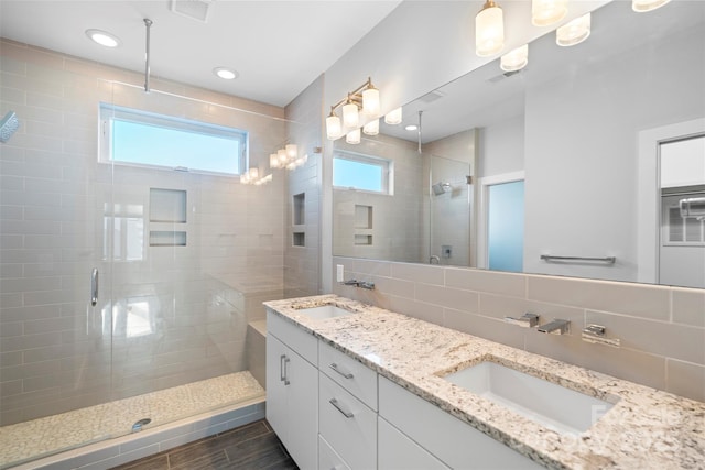 bathroom featuring decorative backsplash, a shower with door, and vanity