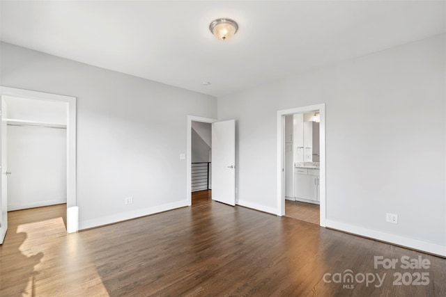 unfurnished bedroom featuring dark hardwood / wood-style flooring, connected bathroom, and a closet