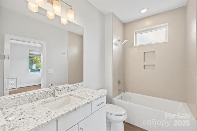 full bathroom with hardwood / wood-style floors, vanity, toilet, and tiled shower / bath