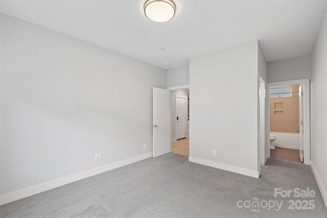 unfurnished bedroom featuring light carpet and connected bathroom