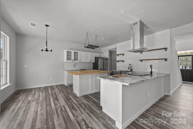 kitchen with tasteful backsplash, ventilation hood, hardwood / wood-style floors, white cabinets, and kitchen peninsula