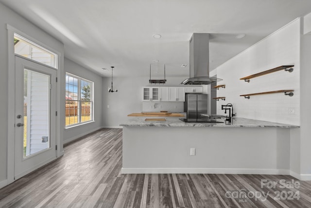 kitchen with island exhaust hood, light wood-type flooring, stainless steel refrigerator, white cabinets, and kitchen peninsula