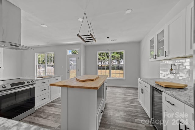 kitchen featuring white cabinets, beverage cooler, a kitchen island, and electric stove